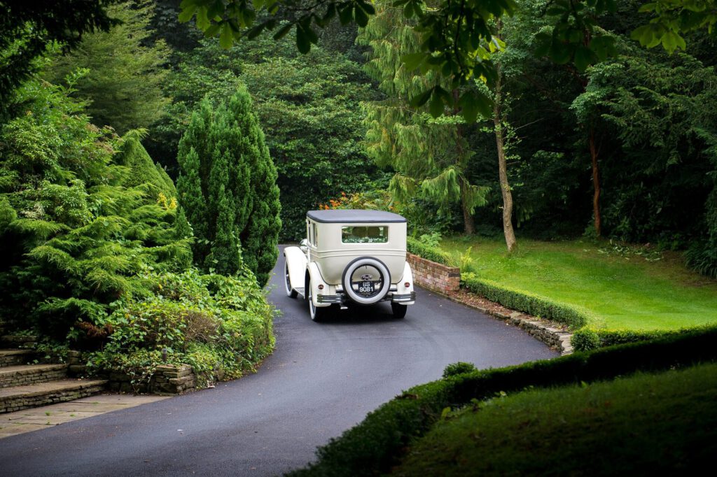 Hochzeitsauto vor grüner Allee